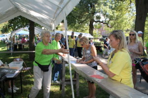 Sister Angela Marie Fitzpatrick, left, reaches for tickets from Betsy Mullins, far right, director of development for the Ursuline Sisters who was in charge of the picnic. Sister Angela was working in the Quilt of the Month Club booth.