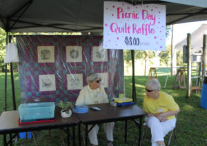 Sister Julia Head, left, and Sister Marcella Schrant sit in the Quilt of the Day Raffle booth. One lucky winner was able to win the quilt hanging in the back of the booth.