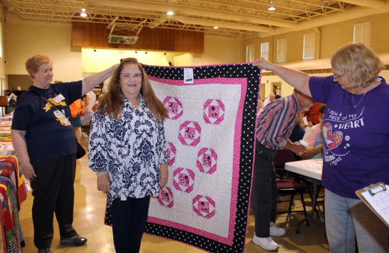 Bonnie Drury of Henderson, Ky., smiles after choosing a Minnie Mouse quilt for her bingo win. Holding the quilt are Sister Helena Fischer, left, and Ann Jacobs, a volunteer.