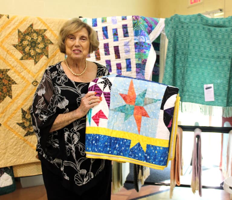 Diane McCauley of Bardstown, Ky., holds her winning prize, the “Stars of the Galaxy” quilt.