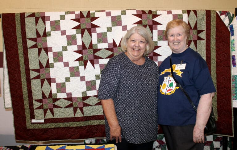Gloria Boarman of Owensboro, a two-time winner, was congratulated by Sister Helena Fischer in front of the “Burgundy Stars” quilt she selected.