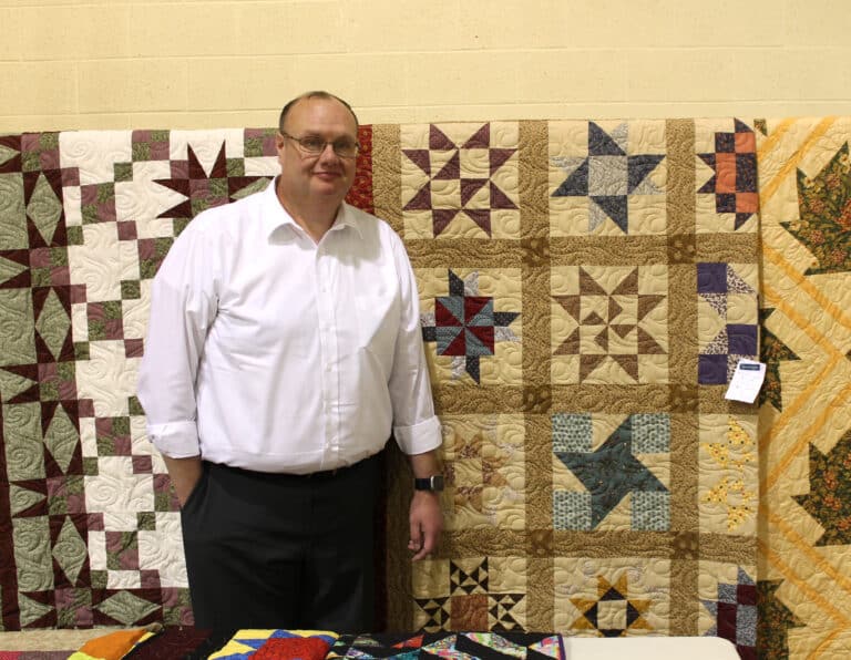 Jerry Dickenson of Greenville, Ky., stands next to the quilt he won titled “Civil War Fabric Sampler.”