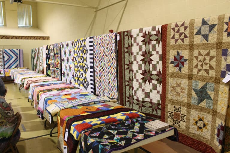 More than 100 quilts were on display on the walls and tables in Maple Hall prior to the start of Quilt Bingo. Several handmade shawls were also available. The remaining quilts and shawls will be available for sale this fall.