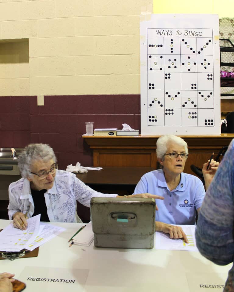 Sister Ann Patrice Cecil, left, and Sister Barbara Jean Head help check in people at one of the registration tables.