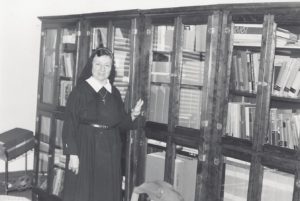 Sister Mary John stands proudly with bookcases she built.