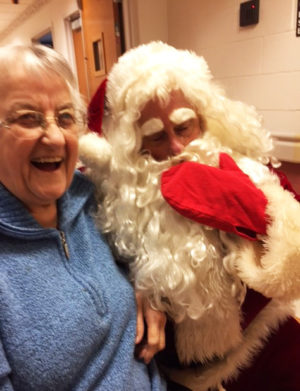 Sister Dorothy Helbling laughs as she poses with Santa, who had a little trouble with his beard.