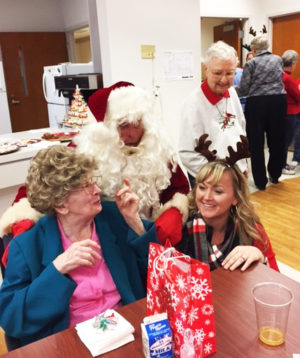 Santa tries to find out if Sister Mary Patrick McDonagh has been naughty or nice this year, as Betsy Mullins and Sister Marie Bosco Wathen look on.