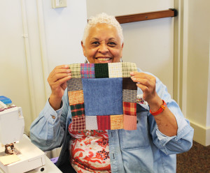 Sheila Gravely, who was attending her first Quilting Friends, holds one of the blocks she made from donated fabric.