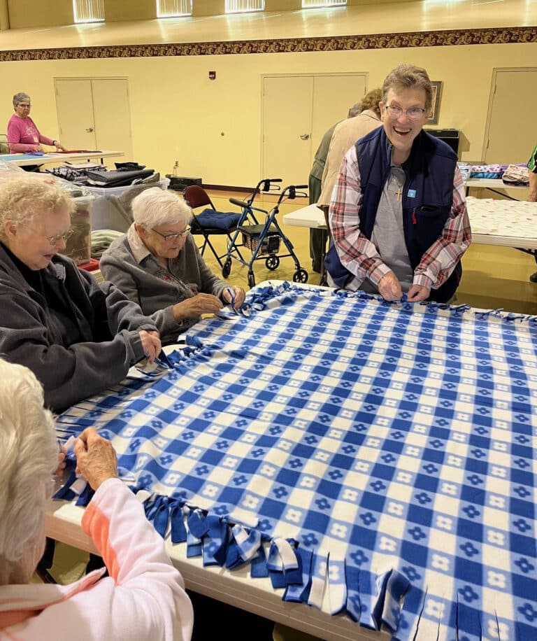Sister Sharon Sullivan, standing, the congregational leader of the Ursuline Sisters, joins in the blanket making with Sister George Mary Hagan, Sister Marie Joseph Coomes and Sister Elaine Burke.