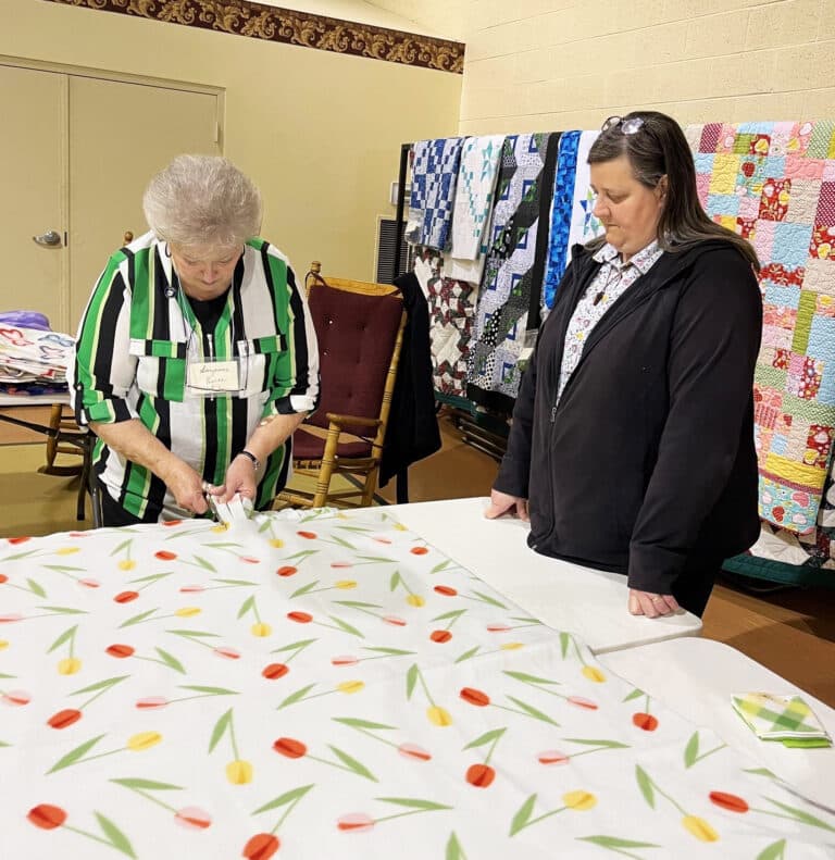 Sister Monica Seaton, right, gets instruction from Ursuline Associate Suzanne Reiss on how to cut the fabric to make it into blankets.