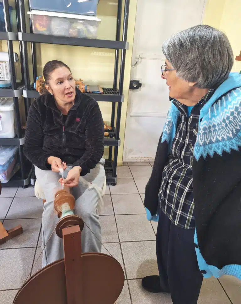 Sister Mimi Ballard talks to a woman while she spins wool at Casa Ursulina. Sister Mimi Ballard talks to a woman while she spins wool at Casa Ursulina.