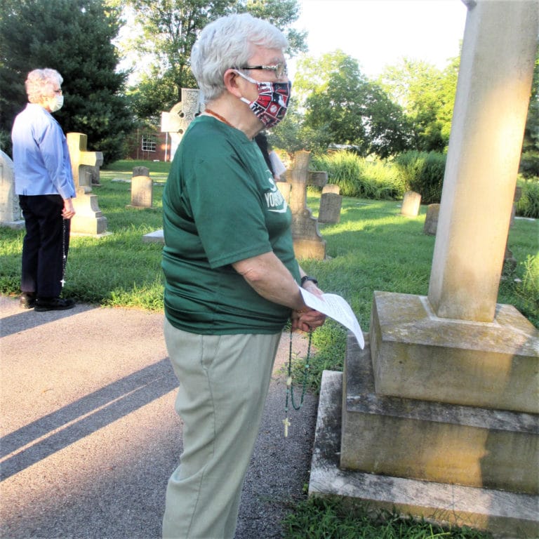 Sister Cecelia Joseph Olinger prays the rosary in the cemetery, wearing her mask and keeping social distance with the rest of the Ursuline Sisters. At left is Sister Ann Patrice Cecil.