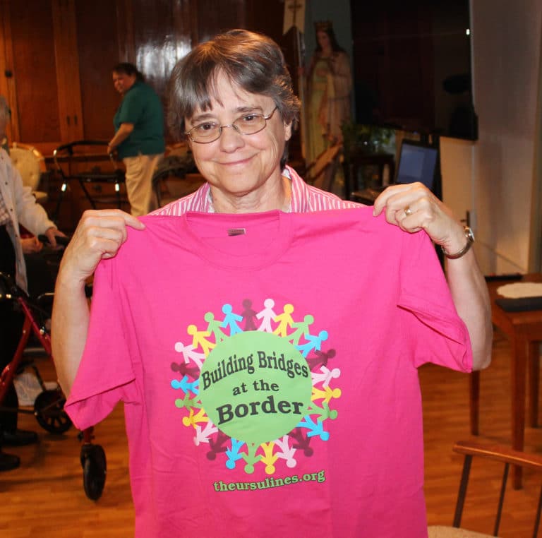 Following her Jan. 8, 2020 presentation to the Ursuline Sisters about her December 2019 experience serving at the Mexican border, Sister Jacinta Powers holds up the T-shirt she wore as part of “Bridges at the Border.”