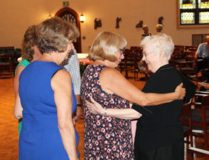 Sister Mary Irene Cecil, right, is overjoyed to see her nieces Winnie Cohron, center, Cathy McClish, center, and Laurie Payne (partially hidden in green) prior to Mass. The three women were among several members of the Riney family who came to support their sister, Sister Judith Nell Riney, who is a new member of the Council.