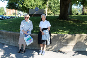 Sister Mary Sheila Higdon, left, and Sister Rose Karen Johnson sit along the curb in front of Mount Saint Joseph Conference and Retreat Center before going to the picnic.