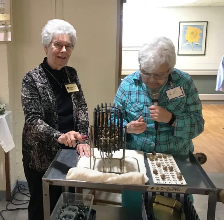 Sister Nancy Murphy, left, spins the bingo balls, as Sister Cecelia Joseph Olinger announces the letter and number. Sister Nancy is on the Council of Religious Steering Committee.