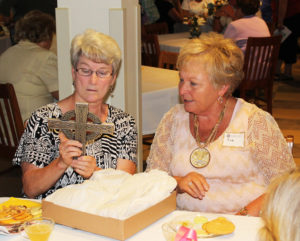 Sister Pam Mueller, left, tries to determine what sort of metal this cross is made of, a gift from the Mills family of Owensboro. Next to her is Sue (Mills) Payne.