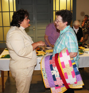 Sister Sharon Sullivan, right, holds her new quilt as she chats with Lisa M. Gulino at the reception. Lisa is a theology professor at Brescia University.