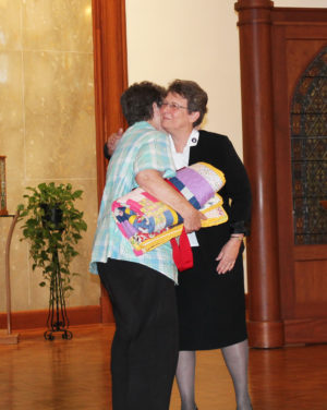 Sister Sharon Sullivan, left, hugs Sister Amelia Stenger after receiving her quilt.