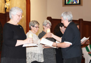 Sister Rita Scott, right, hands her candle to Sister Judith Nell Riney.