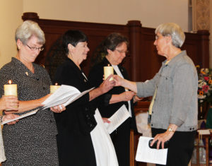 Sister Julia Head, right, hands her candle to Sister Kathleen Condry.
