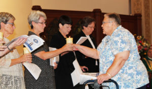Sister Kathleen Dueber, right, offers her candle to Sister Pam Mueller.
