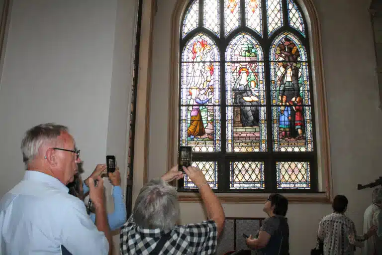 A few of the Louisville visitors take pictures of a stained-glass window in the Chapel. A few of the Louisville visitors take pictures of a stained-glass window in the Chapel.