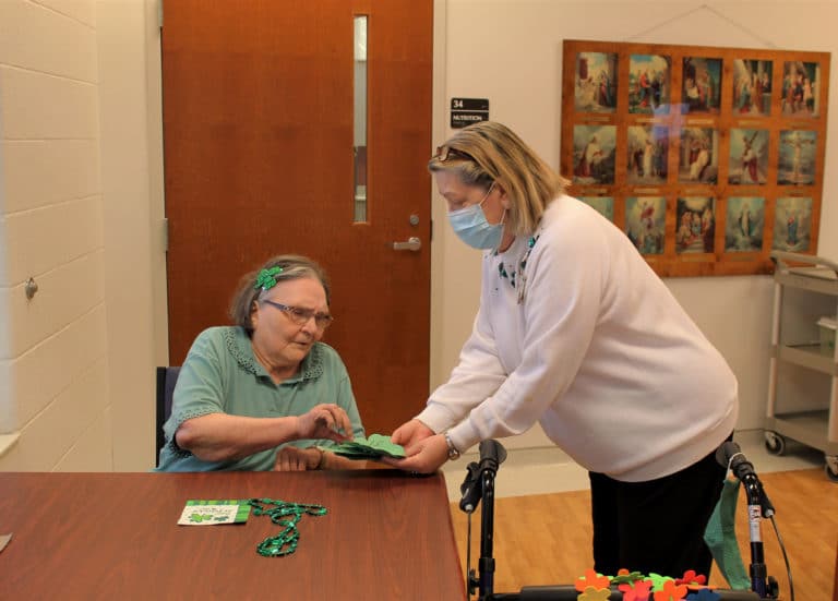 Sister Lois Lindle selects a shamrock with a number on it from Activities Director Debbie Dugger. Sister Lois dressed up her hair with sparkly shamrock barrettes.