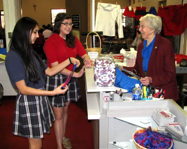 Sister Martina Rockers waits on a couple of Bishop Miege students in the Stag Shop in 2011. After her full-time teaching days were over at Bishop Miege, Sister Martina ran the Stag Shop each school day during the lunch periods so students could buy school-related clothing or items. Sister Martina Rockers waits on a couple of Bishop Miege students in the Stag Shop in 2011. After her full-time teaching days were over at Bishop Miege, Sister Martina ran the Stag Shop each school day during the lunch periods so students could buy school-related clothing or items.