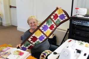 Tish Rudd holds the table runner she is working on.