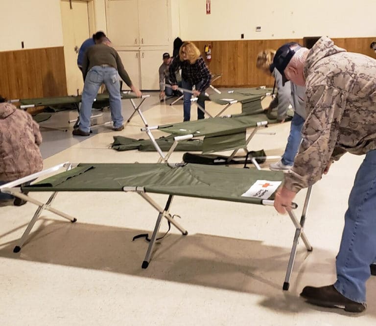 Volunteers set up cots provided by the American Red Cross in the parish hall for displaced people to sleep on Saturday, Dec. 11.