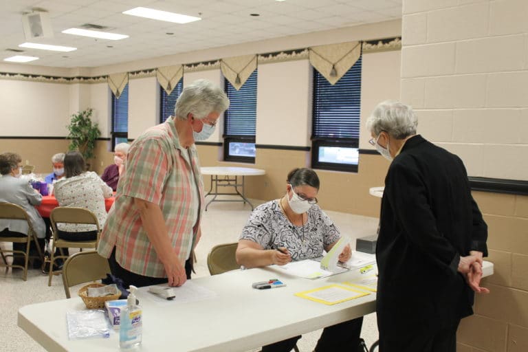 Sister Mary Timothy Bland, standing at left, and Sister Stephany Nelson, seated, look over the registration sheet to find Sister Julia Head, right. Sister Julia is the RCIA coordinator and offers spiritual direction at Immaculate, where the event took place.