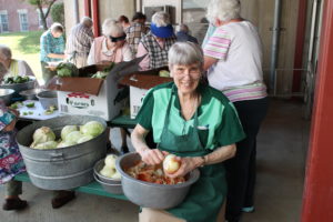 Sister Sheila Anne Smith smiles as she cuts up an onion that will be added to coleslaw served at the picnic.